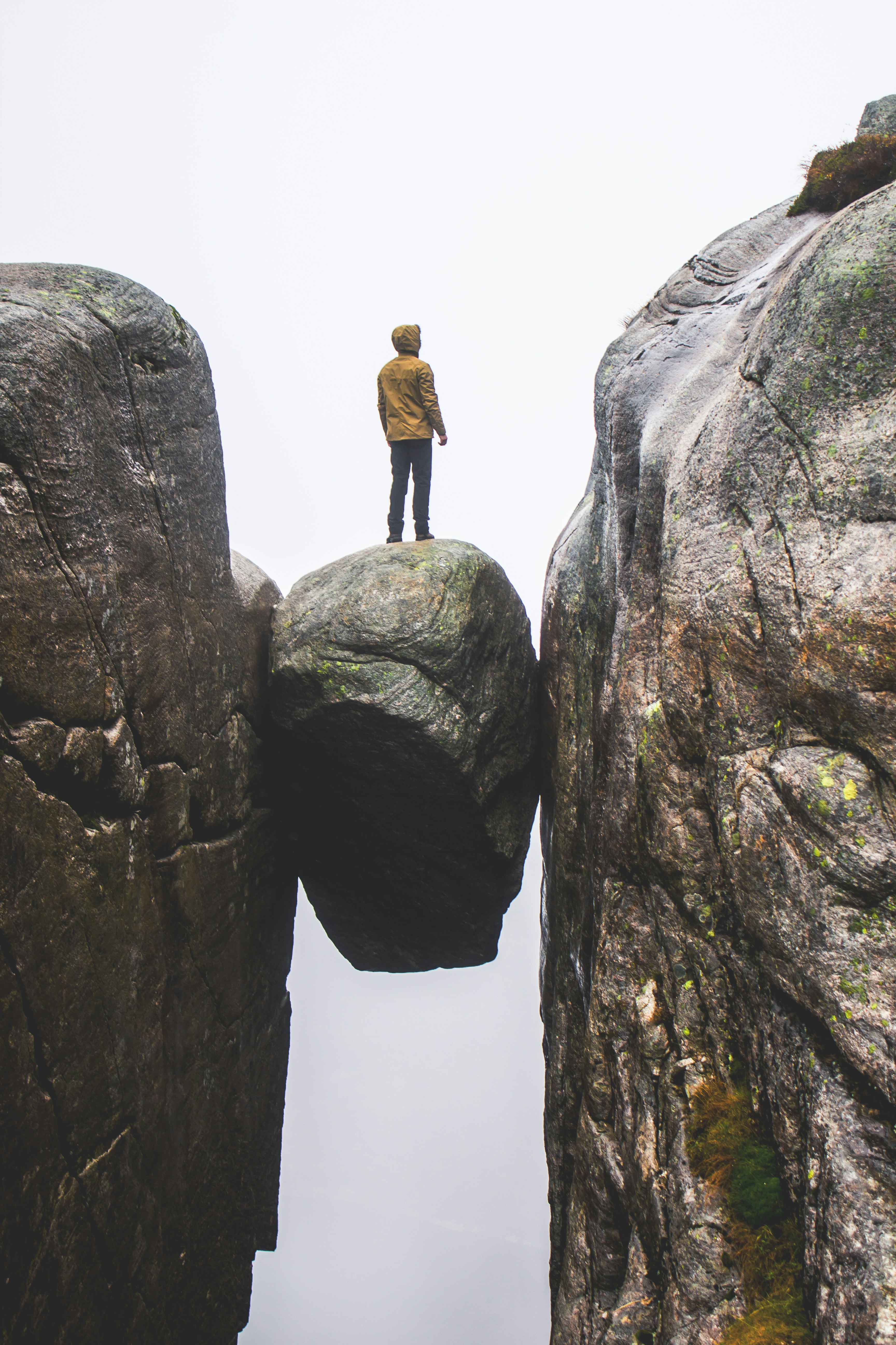 man in black jacket standing on rock formation during daytime